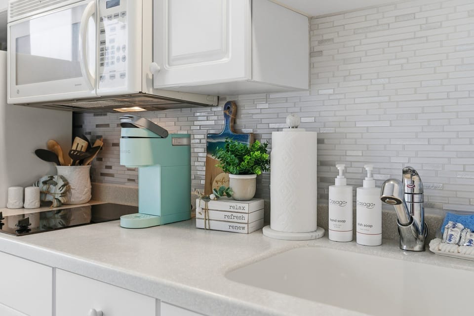Thoughtfully styled kitchenette with coffee maker, sink, and coastal accents. Perfect for morning brews or light meals, adding extra comfort and convenience to your relaxing beach stay.