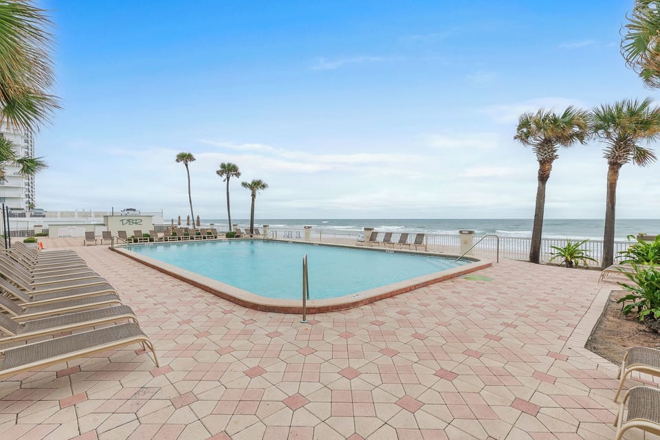 Lounge by the oceanfront pool with palm trees, ocean breezes, and direct beach access. This serene setting is perfect for sun-soaked days and relaxing moments during your beach stay.
