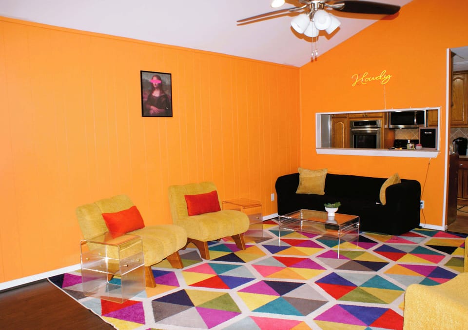 Modern Living & Entertainment: Relax in four comfortable accent chairs with footstools, perfect for coffee or reading. Features a large Smart TV with integrated streaming for high-quality entertainment. Located centrally near the main hallway.