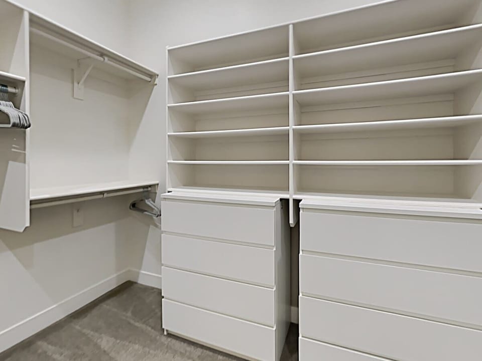 Master bedroom walk-in closet with plentiful built-ins.