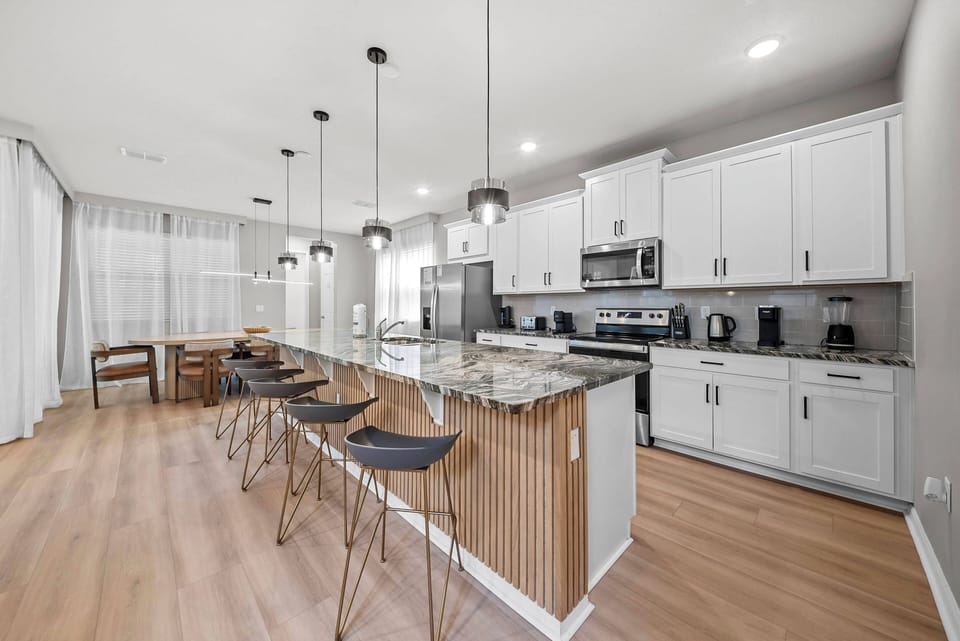 Welcome to a bright kitchen with sleek white cabinetry and warm wood accents, ideal for culinary adventures. The spacious granite island combines style and functionality, while large windows fill the space with natural light.
