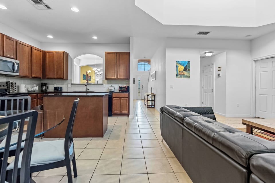 Discover a bright, open space with rich wood cabinetry and sleek stainless steel appliances. The inviting living area, adorned with soft neutral furnishings and warm tile flooring, is perfect for relaxation.