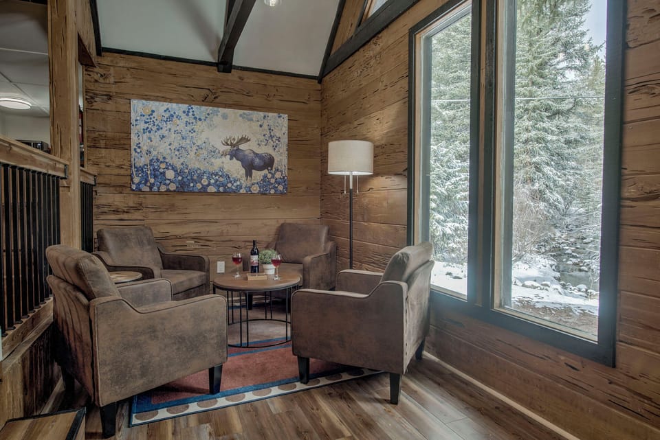 Sip and unwind in your cozy nook—plush seating, warm wood walls, and serene forest views invite you to relax and make this peaceful corner yours.