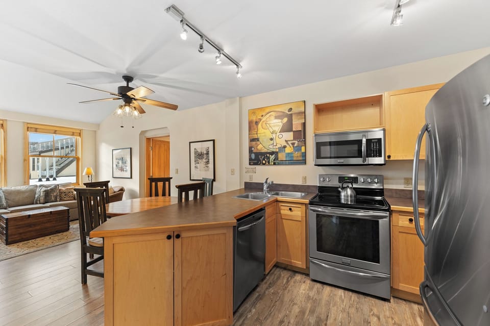 Your open-concept kitchen flows seamlessly into the living area, featuring modern appliances and warm wood cabinetry perfect for preparing meals.