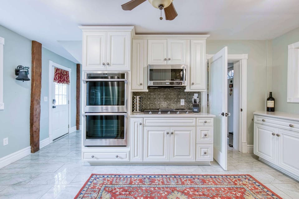 Elegant kitchen showcasing built-in double ovens, refined white cabinetry, and a sophisticated tiled backsplash.