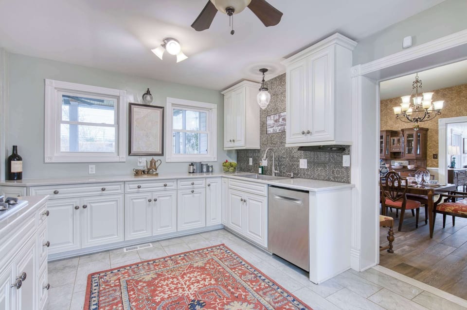 Elegant, light-filled kitchen featuring refined white cabinetry, stainless-steel finishes, and a sophisticated patterned accent wall.