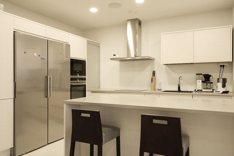 Fully equipped high-end kitchen featuring minimalist white cabinetry and a professional-grade atmosphere.