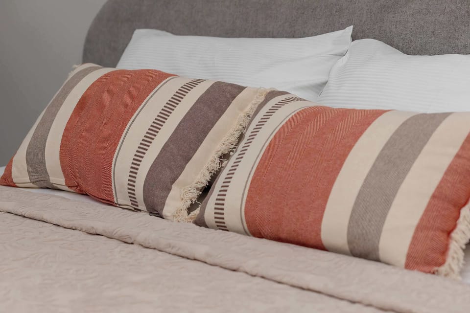 Detailed close-up of decorative cushions and textured bedspread.