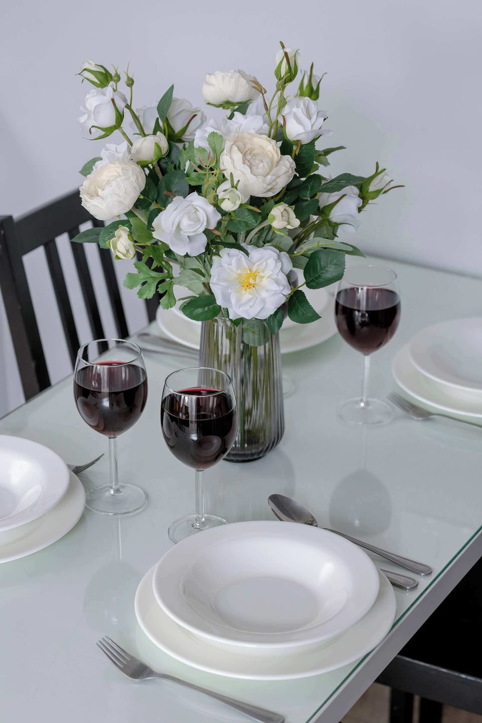 A close-up of a dining table set with plates, cutlery, and floral decorations. The arrangement feels elegant and ready for guests. Neutral colors keep the look refined.