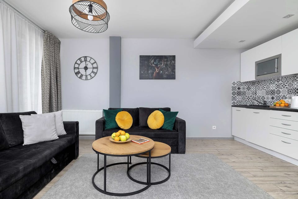 A living room angle highlighting the sofa and coffee table placed near the kitchen. Soft lighting and neutral tones create a balanced look. Decorative accents add subtle color.