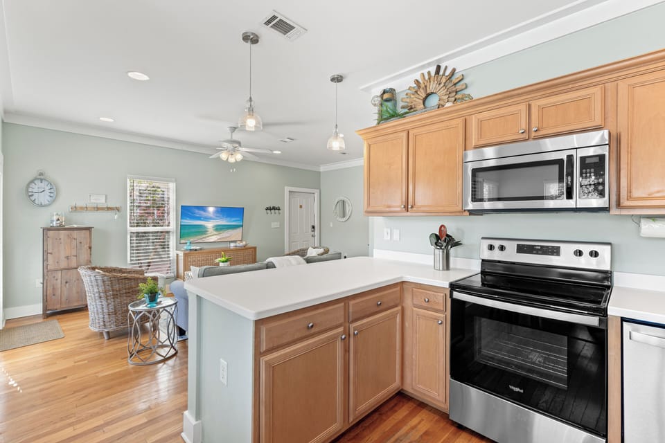 Your fully equipped kitchen features warm wood cabinets, modern appliances, and a spacious island where you can prepare meals while staying connected to the living area.