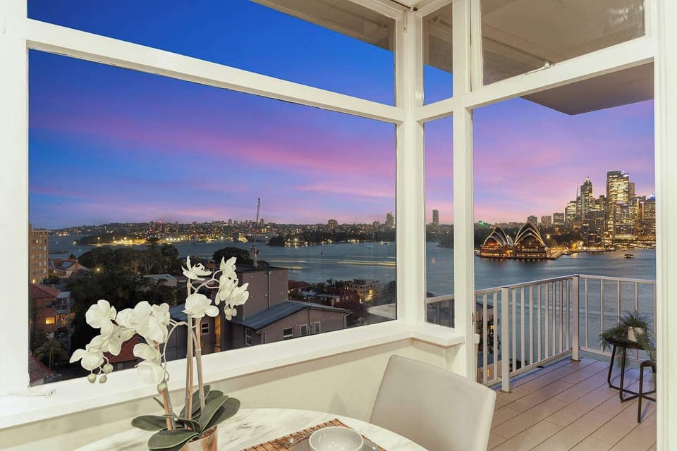 Enclosed balcony/sunroom capturing sparkling night skyline views.