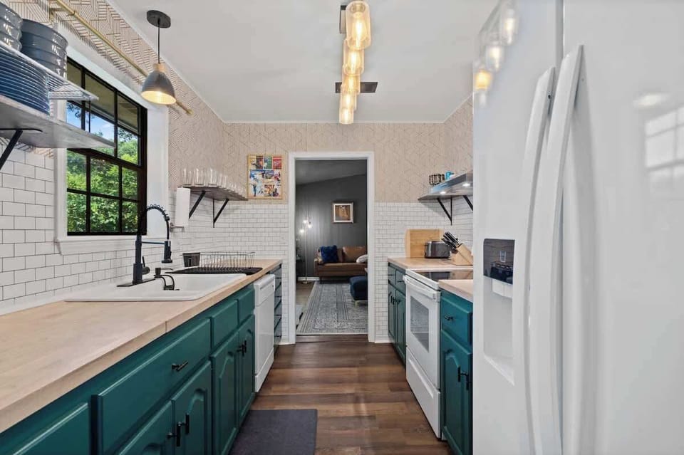 Bright kitchen w/ teal cabinets, open shelving & long counters for prep