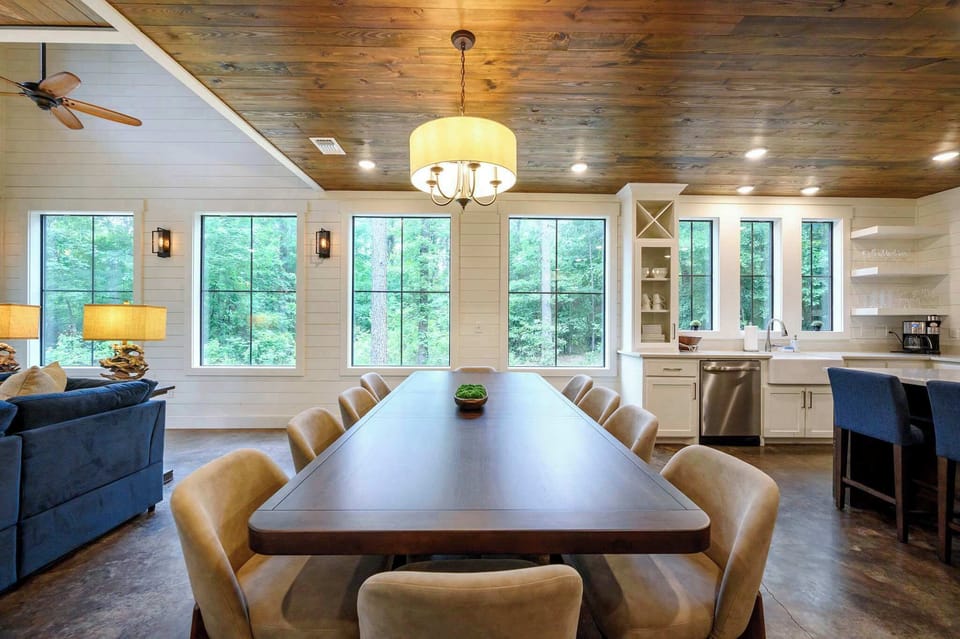 Dinners feel different when the whole crew fits — this long dining table with treeline windows is where group meals become memories.