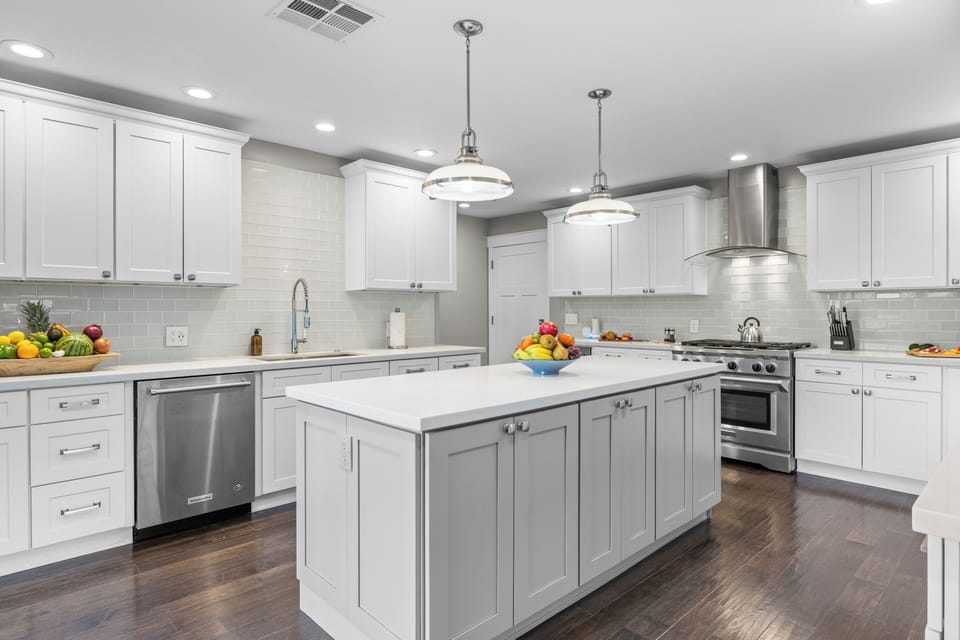 Modern white kitchen with a large center island and stainless steel appliances.