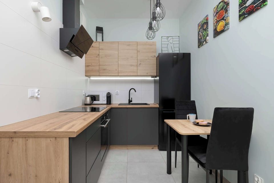 Compact modern kitchenette with dining table and built-in appliances.