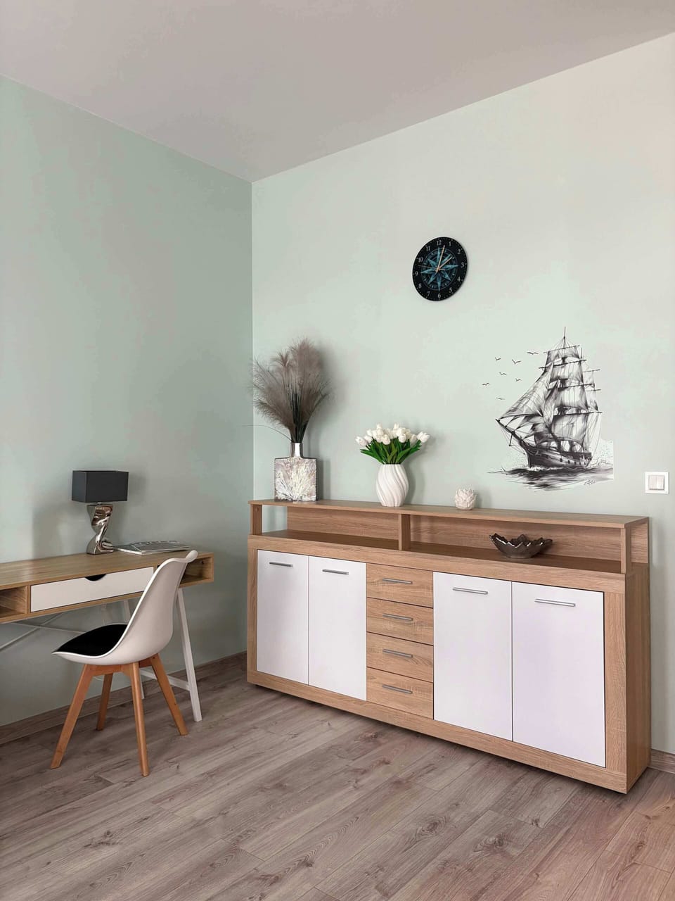 A bright living room with a large chest of drawers and a work area.