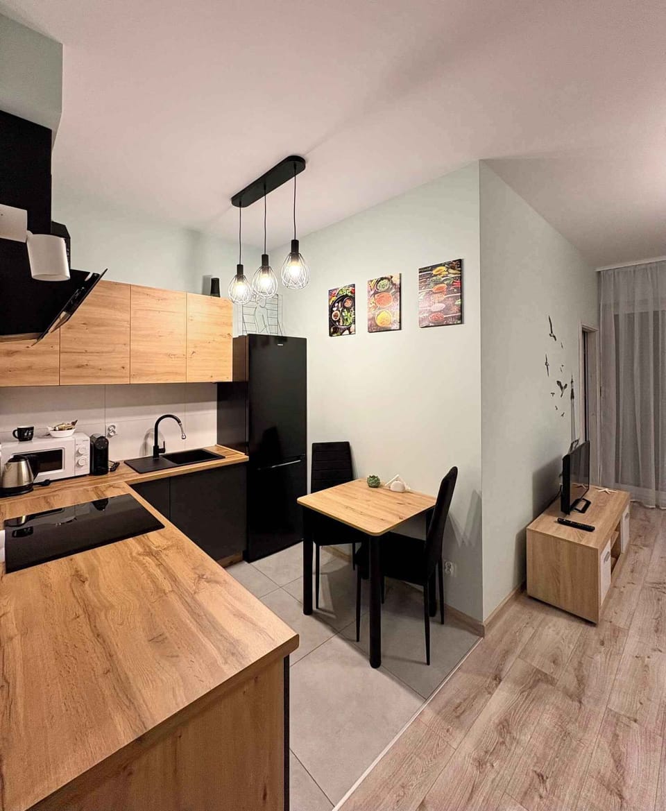 A modern kitchen interior with wooden countertops and light-colored cabinets. Built-in appliances and overhead lighting give the space a clean, contemporary look. The layout appears practical and well suited for everyday cooking.