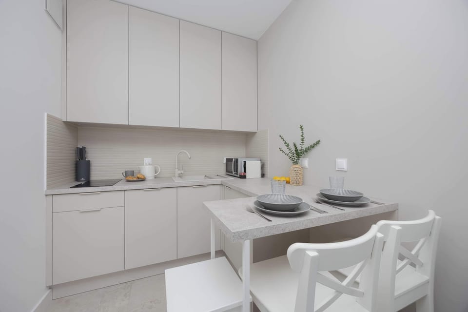 A modern kitchen with white cabinets and built-in appliances. A small dining table sits nearby for everyday meals. The space feels clean and well-organized.