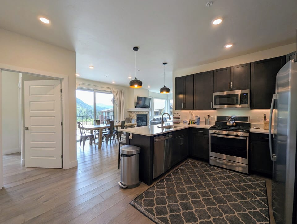 Step into your spacious gourmet kitchen with sleek dark cabinetry, stainless steel appliances, and a bright island perfect for gathering. Through the windows, mountain views frame your every meal.