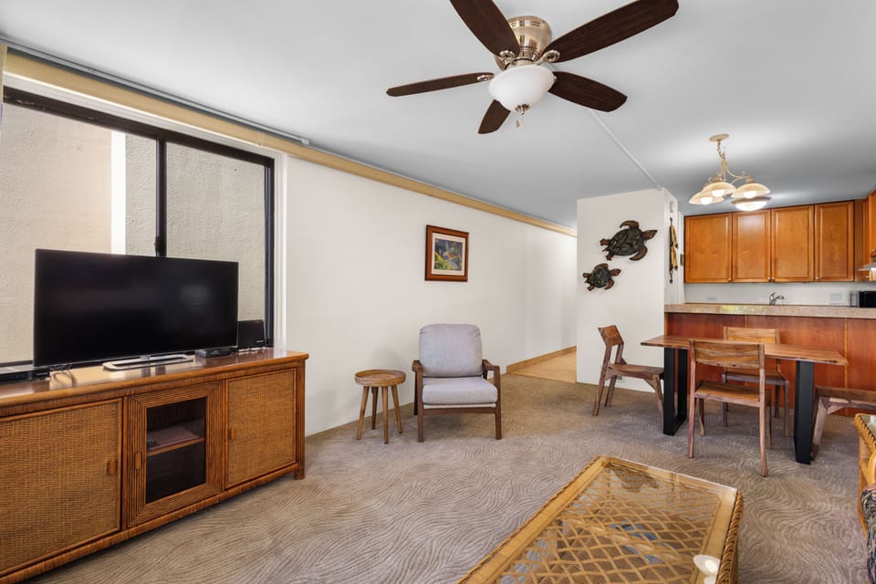 Relax in your comfortable living area with a ceiling fan keeping you cool, a flat-screen TV for entertainment, and a cozy seating arrangement perfect for unwinding after island adventures.