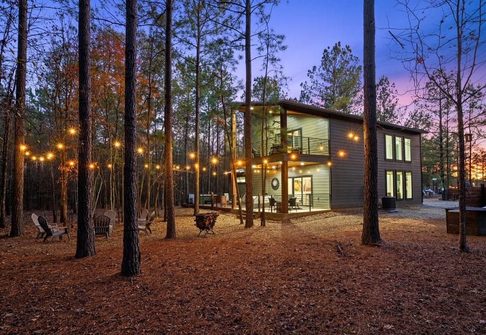 As evening settles in, the soft glow of string lights and warm interior lighting creates a welcoming, cozy atmosphere outdoors.