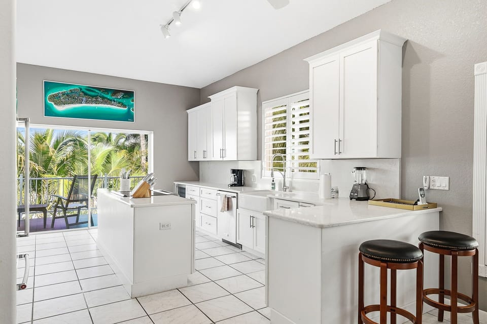 Your fully equipped kitchen features modern appliances, granite countertops, and a breakfast bar where you can enjoy morning coffee while palm trees sway outside your window.