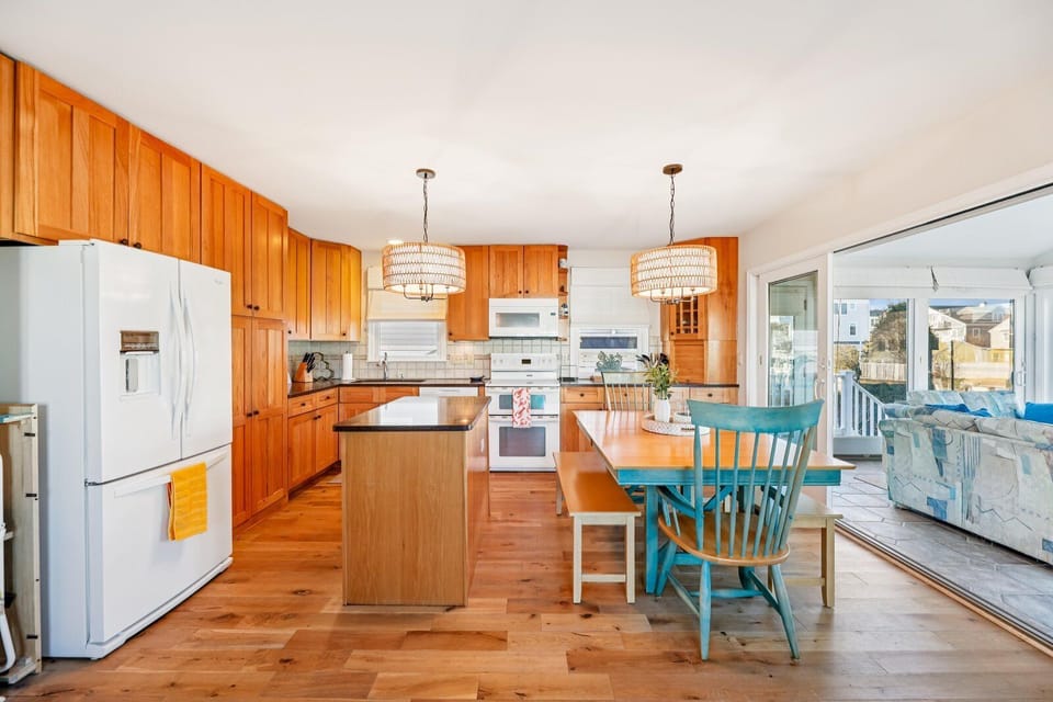 Picture yourself sipping morning coffee at this cheerful table, sunlight streaming in through the windows. The spacious kitchen invites you to whip up your favorite meals while enjoying the open, breezy coastal vibe.