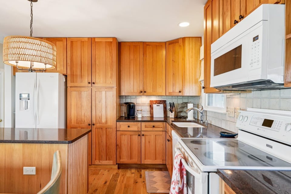 Step into your vacation kitchen, complete with warm wood cabinetry, modern appliances, and all the essentials for preparing delicious home-cooked meals during your stay.