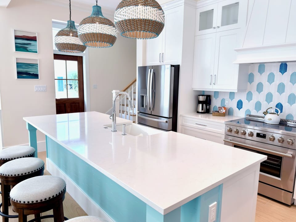 Open-concept kitchen with island seating, appliances, and coastal-modern style