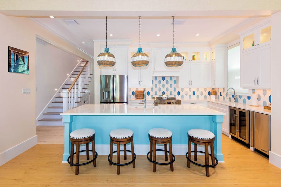 Open-concept kitchen with island seating, appliances, and coastal-modern style
