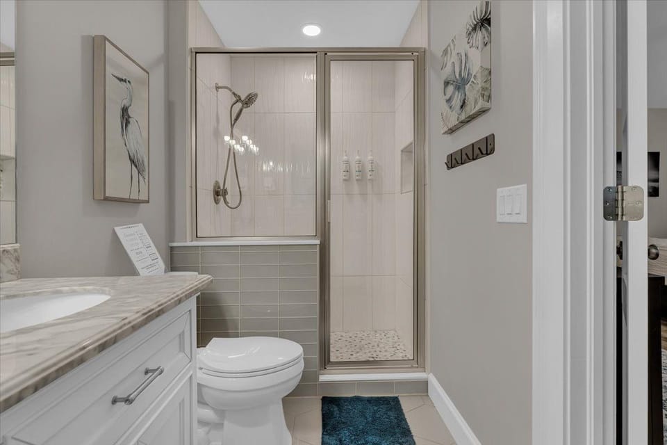 Bathroom featuring a stone-topped vanity and glass-enclosed walk-in shower.