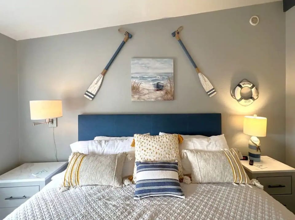 Bedroom with coastal decor, blue headboard, and bedside tables.