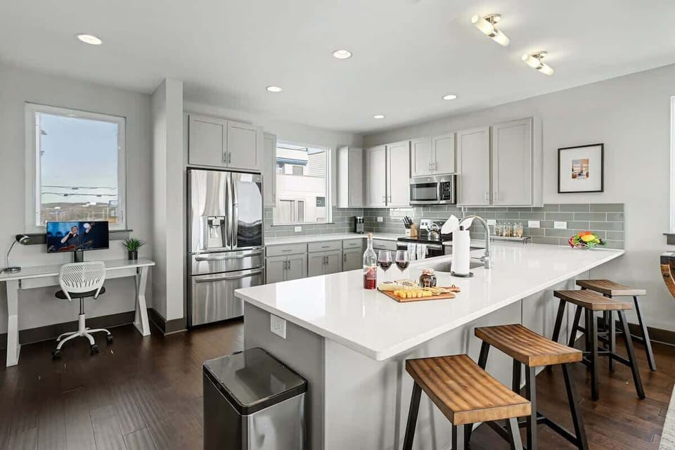 2nd Floor: Fully equipped kitchen with stainless steel appliances, ample counter space with seating for 4 guests, and a workstation with a monitor and desk chair.