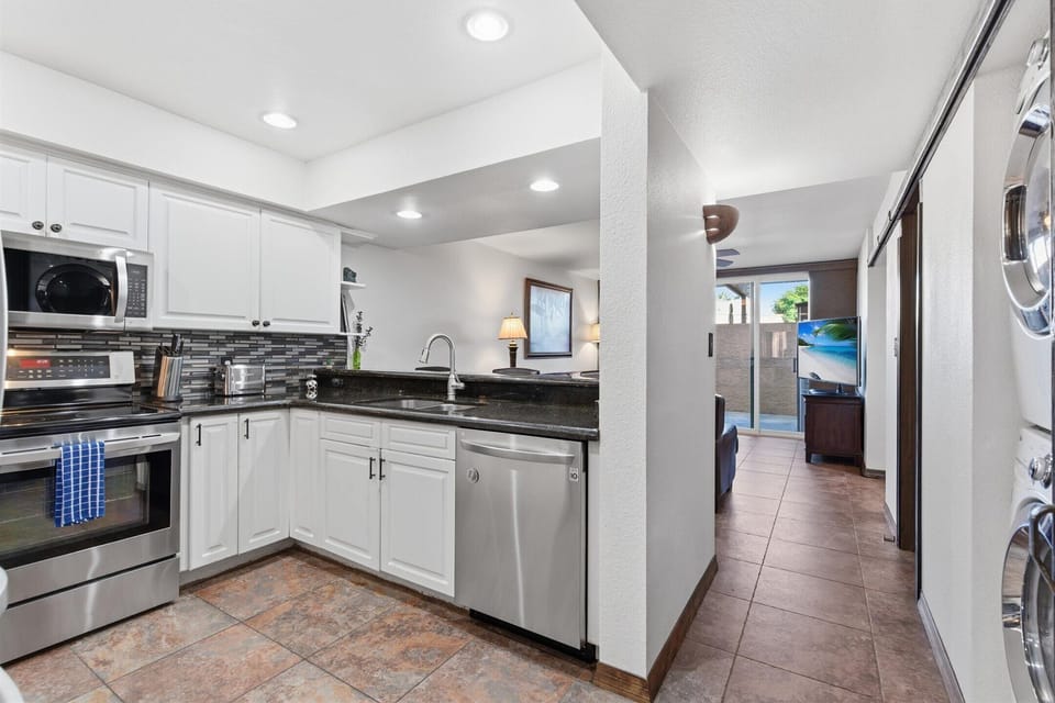 Fully equipped kitchen with stainless steel appliances, bar seating for three, and a convenient laundry area with a washer and dryer.