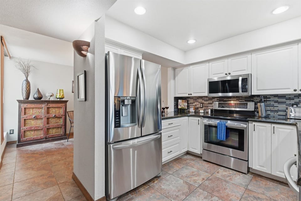 Fully equipped kitchen with stainless steel appliances, bar seating for three, and a convenient laundry area with a washer and dryer.