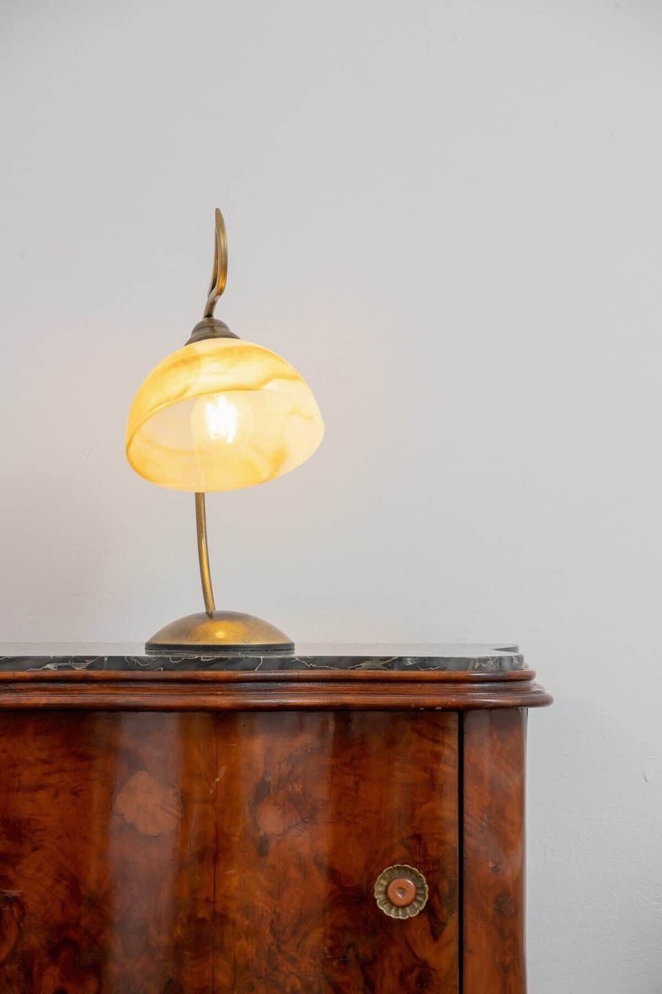 An antique wooden chest of drawers with a night lamp on it.