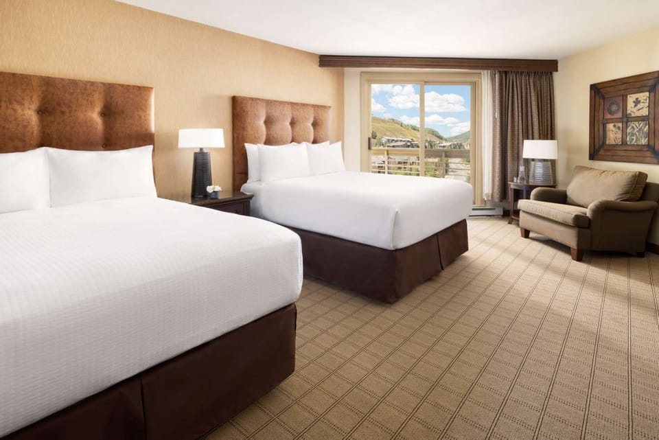 Two queen beds with soft lighting and seating space