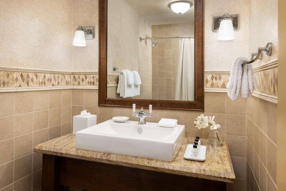 Clean bathroom with sink, mirror, towels, and shower