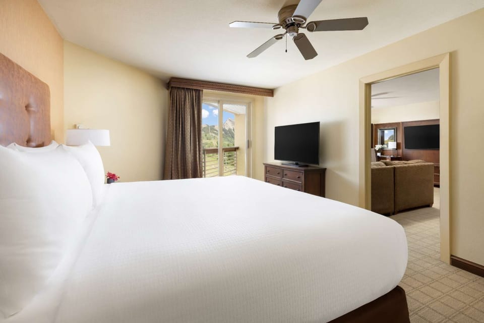 Bright bedroom with king bed, TV, and balcony doors