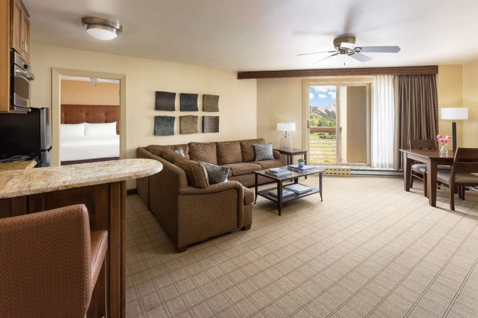 Open living room with sofa, kitchen area, and mountain views