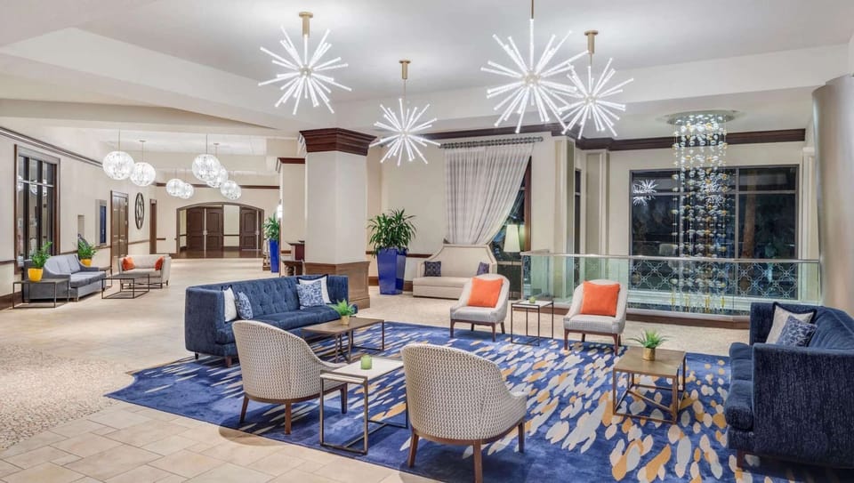 Bright lobby with stylish seating, chandeliers, and blue accent rug