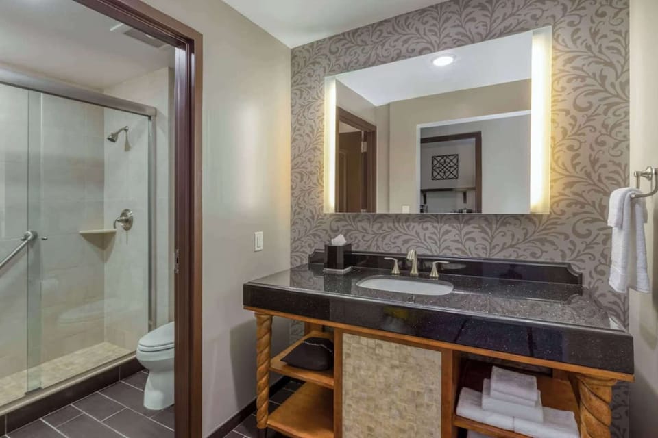 Bathroom with glass shower, large mirror, and bright vanity lighting