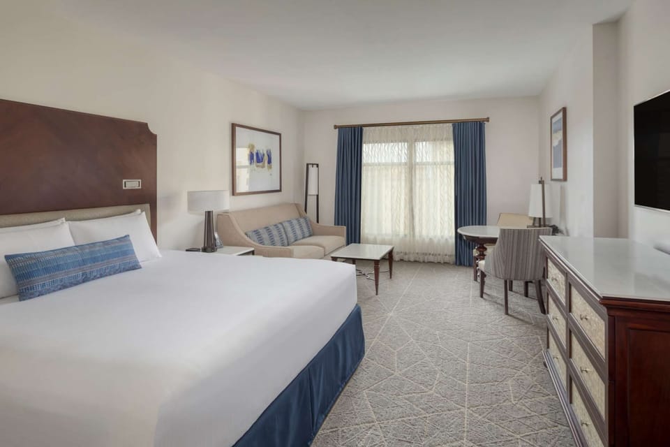 Spacious king room with sofa, table, and large window view