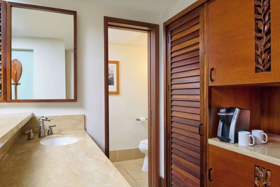 Spacious bathroom with marble counter, wood cabinets, and coffee maker