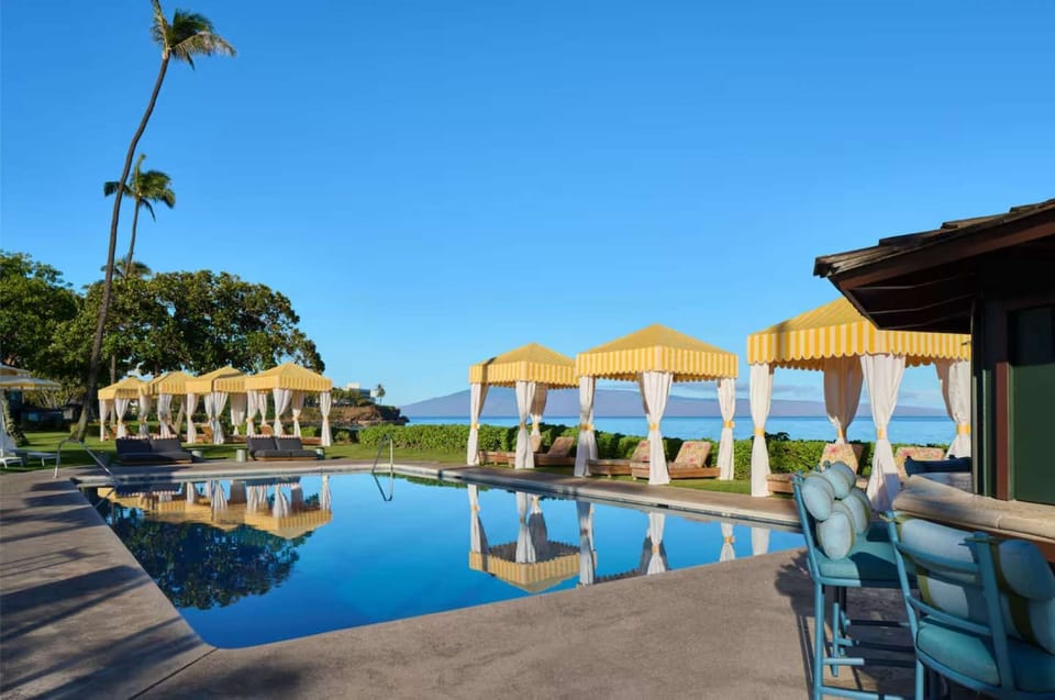 Poolside cabanas with ocean views and sunny skies all around