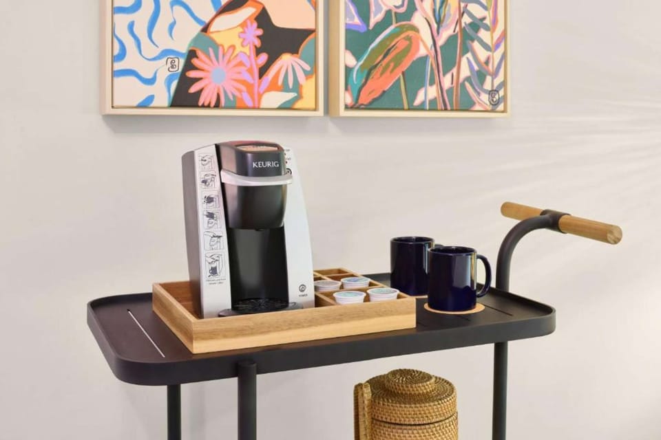 Keurig coffee station with mugs, pods, and colorful wall art
