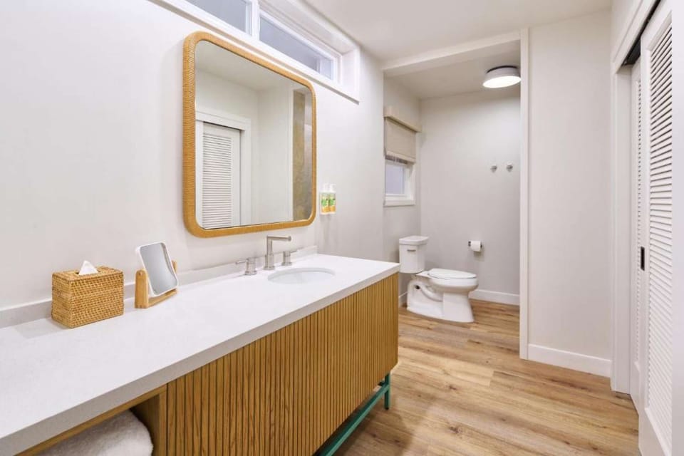 Spacious bathroom with long vanity, wood floors, and soft light
