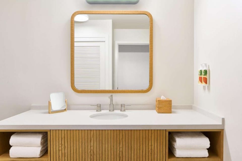 Bright bathroom with wood vanity, round mirror, and soft lighting