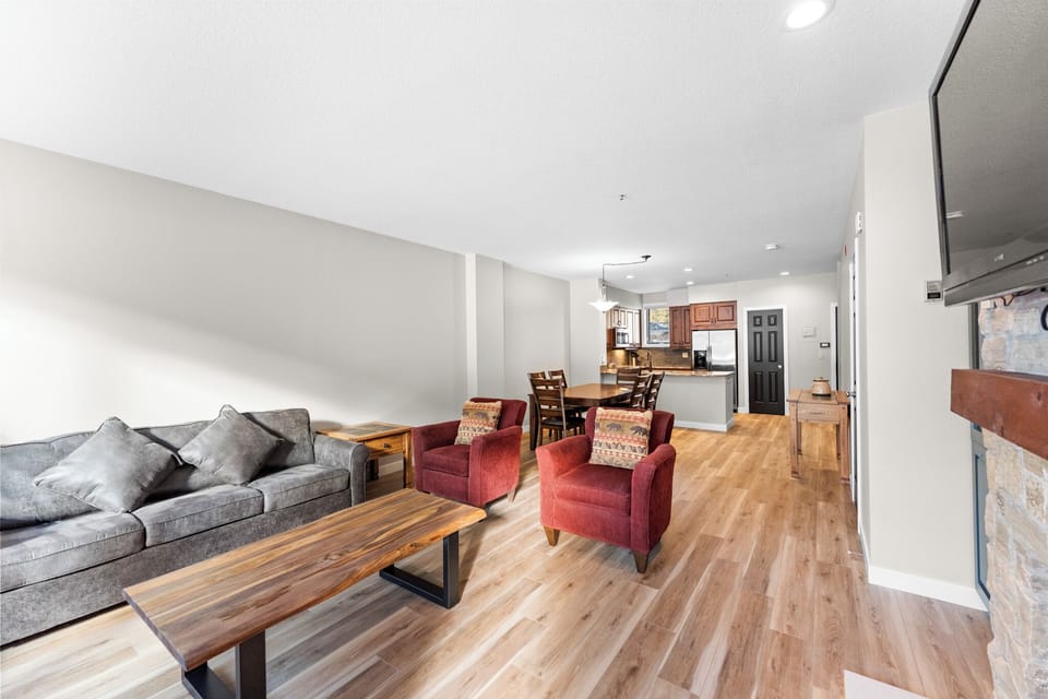 Relax in your spacious open-concept living area with comfortable seating, warm wood floors, and seamless flow to the fully-equipped kitchen.
